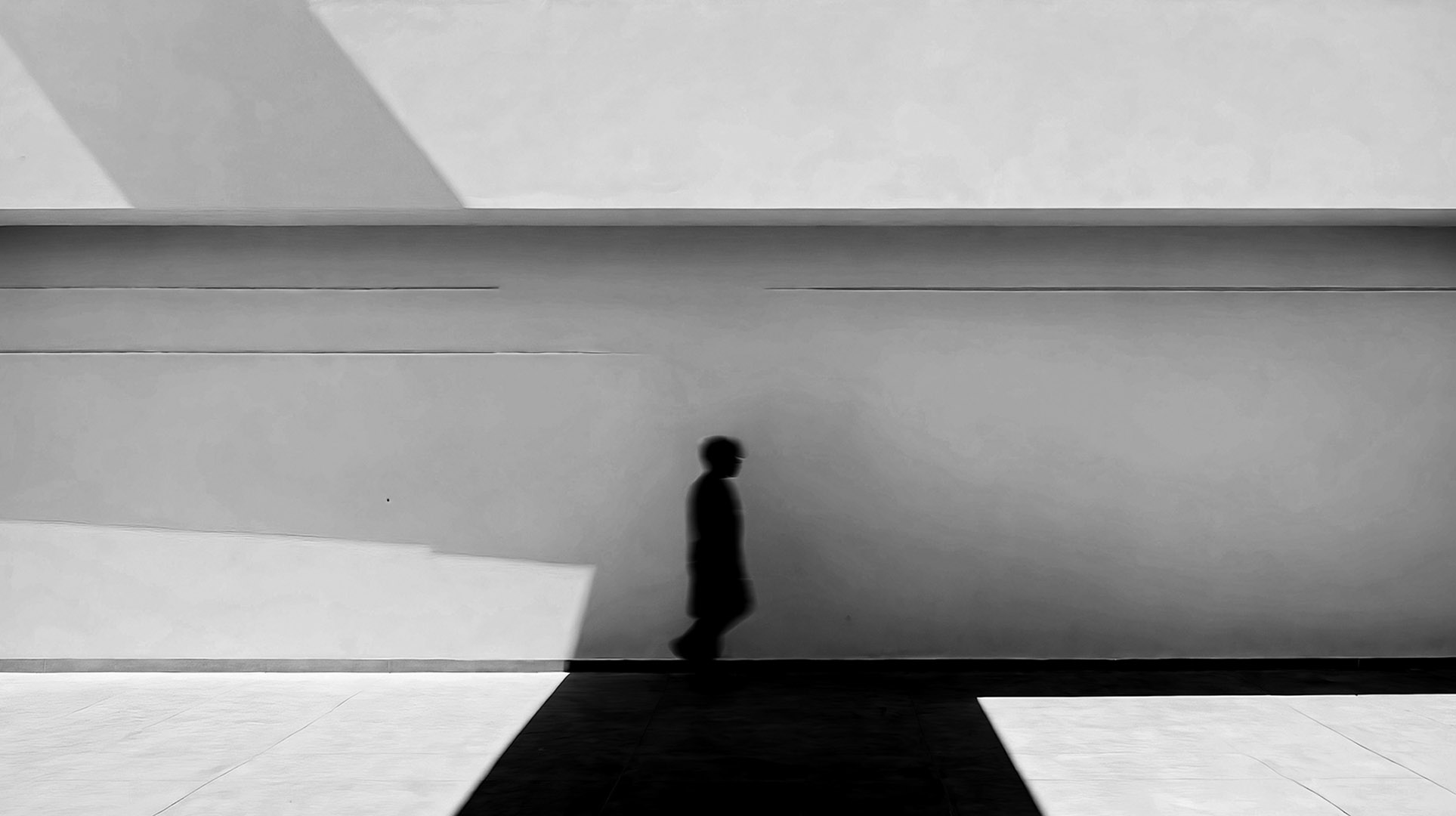 Silhouette of a man walking through the sidewalk.